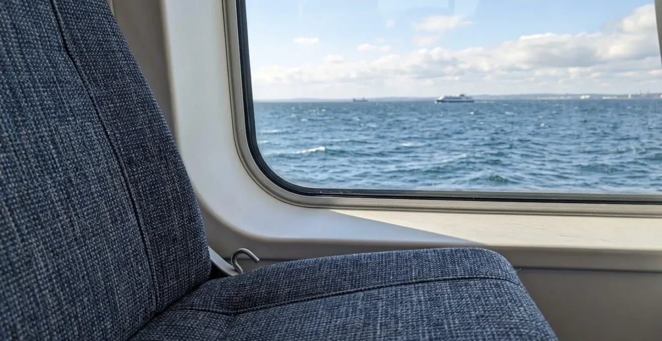 Primo piano ravvicinato di un sedile moderno all'interno di un traghetto con finestra che affaccia sul mare